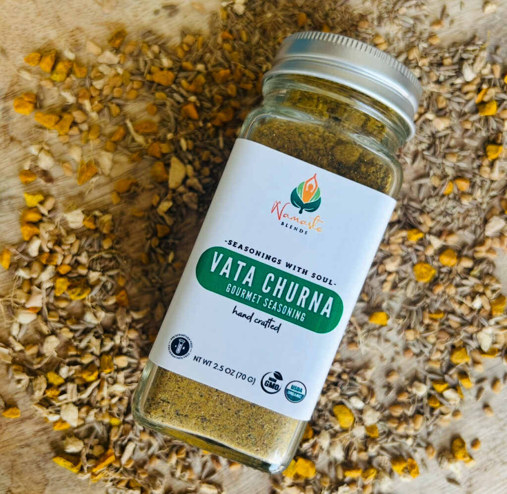 A bowl of Vata Churna seasoning with aromatic spices, including a blend of warming herbs, next to a wooden spoon and fresh ingredients. A balancing Ayurvedic spice mix for grounding and digestion.