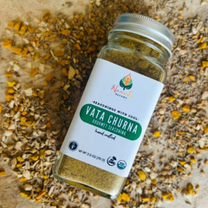 A bowl of Vata Churna seasoning with aromatic spices, including a blend of warming herbs, next to a wooden spoon and fresh ingredients. A balancing Ayurvedic spice mix for grounding and digestion.