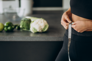 A collection of Ayurvedic herbs for weight loss, including Triphala, Guggul, Punarnava, Fenugreek, and Turmeric, displayed in wooden bowls with a mortar and pestle, symbolizing natural weight management through Ayurveda.