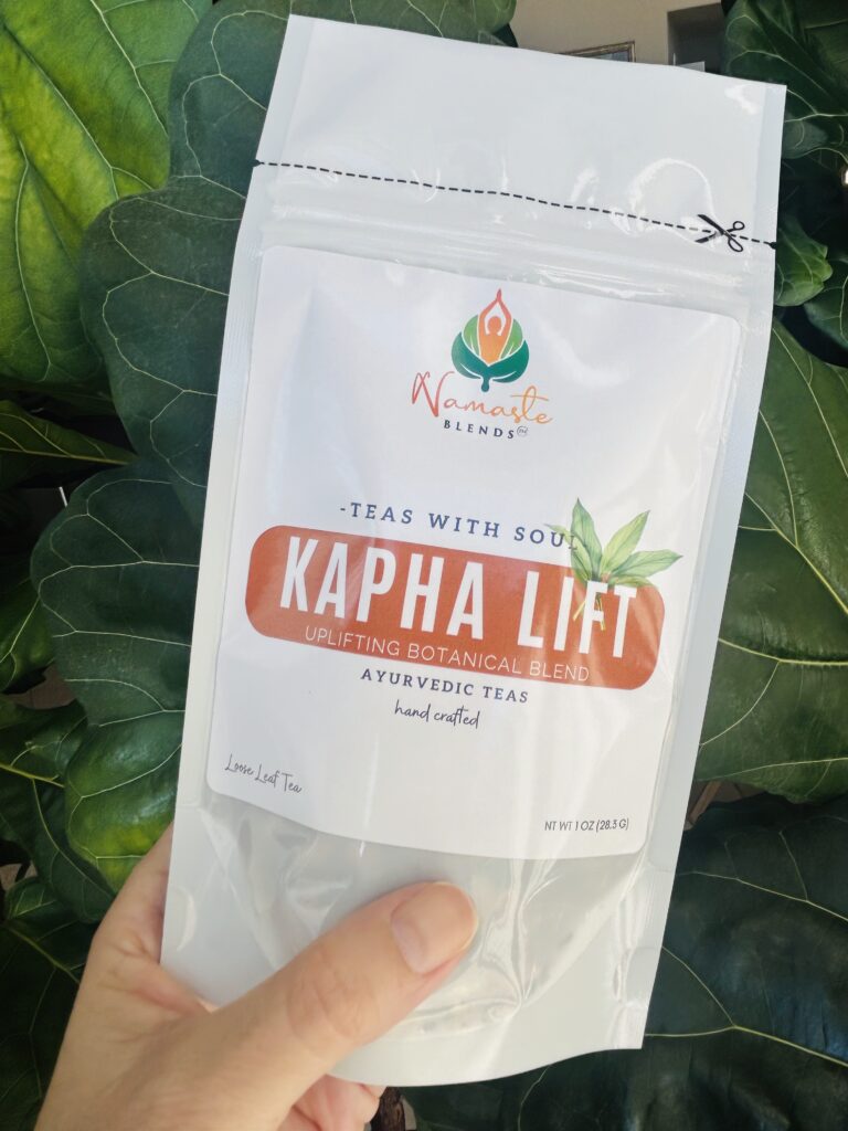 kapha lift herbal tea bags displayed in a minimalist setting with a white mug and warm neutral tones, caffeine free herbal tea sachets with visible spices like ginger clove and citrus pieces, energizing botanical blend designed for daily wellness rituals and mindful living, cozy tea aesthetic, herbal tea for energy and balance routine, wellness tea gift idea, tea bags presentation for self care and uplifting lifestyle