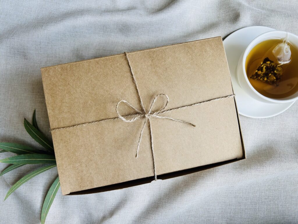 self care gift box displayed in a minimalist setting with a white mug and soft neutral tones, curated wellness set featuring herbal tea bags, lavender eye pillow, pillow mist, magnesium bath flakes and wooden spoon, calming spa gift aesthetic, relaxation gift box for stress relief and mindful living, cozy self care ritual set, wellness gift presentation for comfort and peaceful lifestyle