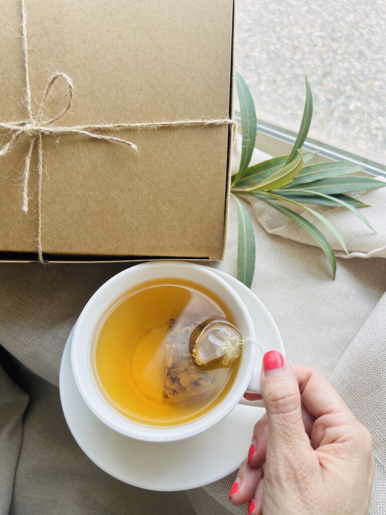 self care gift box displayed in a minimalist setting with a white mug and soft neutral tones, curated wellness set featuring herbal tea bags, lavender eye pillow, pillow mist, magnesium bath flakes and wooden spoon, calming spa gift aesthetic, relaxation gift box for stress relief and mindful living, cozy self care ritual set, wellness gift presentation for comfort and peaceful lifestyle